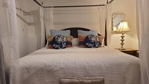 A neatly made bed with a canopy, a bedside lamp, and a mirror on the wall. - Elegance & Style With Custom Canopy Beds (Halifax)