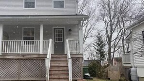 A two-story house with a front porch, a staircase, and a fenced yard. - Elegance & Style With Custom Canopy Beds (Halifax)