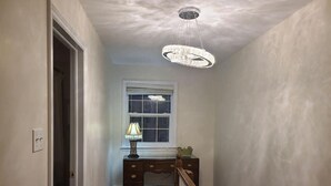 A hallway with a wooden staircase, a desk with a lamp, and a ceiling light fixture. - Elegance & Style With Custom Canopy Beds (Halifax)