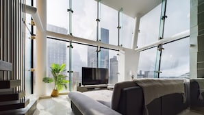 A modern living room with a large window, a flat-screen TV, and a sofa. - Amazing Skyline Views 3BR Duplex (Manchester)