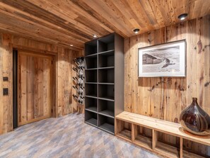 A wooden interior with a wine rack, a framed picture, and a bench. - Family chalet with pool and pets allowed near slopes (Courchevel)