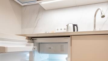A compact kitchen with a built-in microwave, a stainless steel sink, and a refrigerator with a water dispenser.
