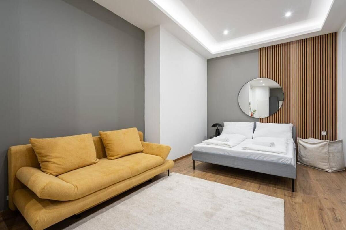 Une chambre à coucher moderne avec un canapé, un lit et un grand miroir rond accroché au mur.