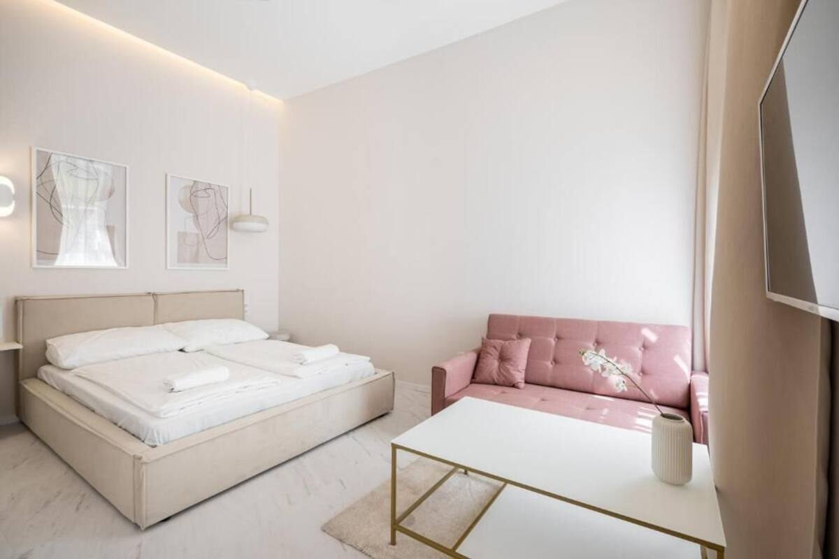 Une chambre à coucher moderne avec un lit, un canapé rose et une table basse blanche.