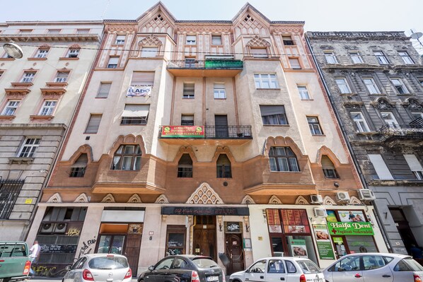 A multi-story building with a central entrance, a sign for a restaurant, and a sign for a dental clinic. - A13 - Boutique Apartments by BQA (Budapest)