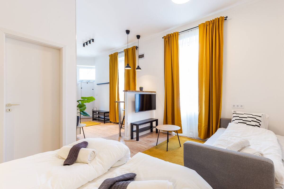 Une chambre d’hôtel avec deux lits, une télévision, une petite table et un canapé.