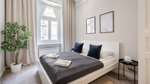 Un dormitorio moderno con una cama grande, una planta en maceta y dos cuadros en la pared.