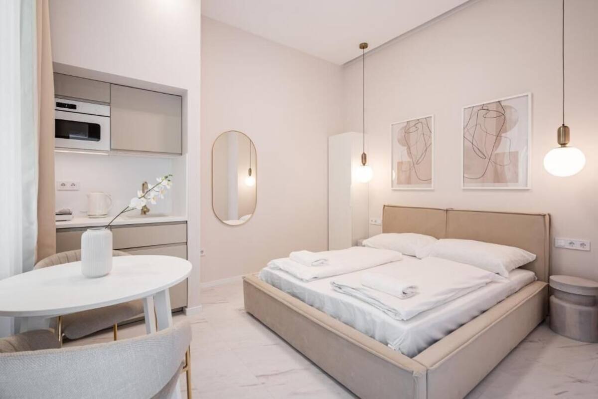 Une chambre d’hôtel moderne équipée d’un lit, d’une table de salle à manger ronde, d’un petit coin cuisine et d’une poubelle.