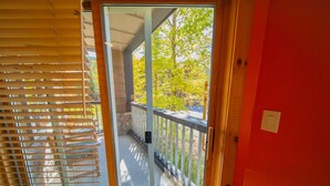 A balcony with a wooden railing, a glass door, and a view of trees and a building. - Corner Unit w/Mountain Views, River Run Village (Keystone)
