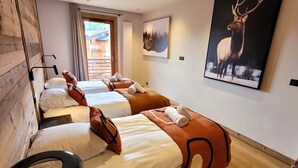 Et hotelværelse med to senge, en træpanelvæg, et stort billede af en elg og udsigt til en bygning gennem vinduet.