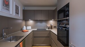 Et moderne køkken med rustfrie hvidevarer, indbygget ovn og mikroovn.