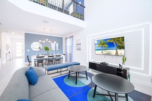 Un salon moderne avec un canapé, une table basse ronde et un coin repas comprenant des chaises et une table.