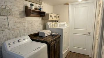 Un espace buanderie comprenant un lave-linge, un sèche-linge et des piles de serviettes.