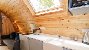 A compact kitchen with a wooden ceiling, a built-in sink, and a toaster. - Conwy Pod (Llanrwst)