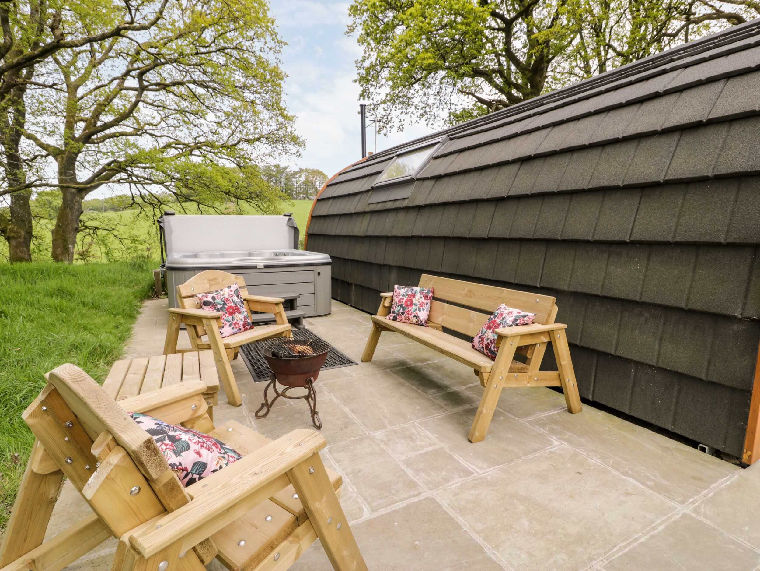 An outdoor patio with wooden furniture, a grill, and a hot tub.