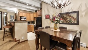 A spacious dining area with a wooden table, leather chairs, and a large mirror above. - Winterwood 11 – Cozy 3BR Mountain Townhome with Sauna and Creek Views! (Steamboat Springs)