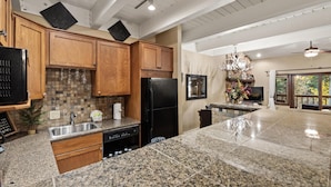 A spacious kitchen with granite countertops, wooden cabinets, and a black refrigerator. - Winterwood 11 – Cozy 3BR Mountain Townhome with Sauna and Creek Views! (Steamboat Springs)