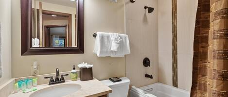 A bathroom with a sink, mirror, toilet, and bathtub.