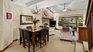 A spacious living area with a fireplace, dining table, and comfortable seating. - Winterwood 11 – Cozy 3BR Mountain Townhome with Sauna and Creek Views! (Steamboat Springs)