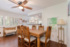 A dining area with a wooden table and chairs, a ceiling fan, and a map on the wall.