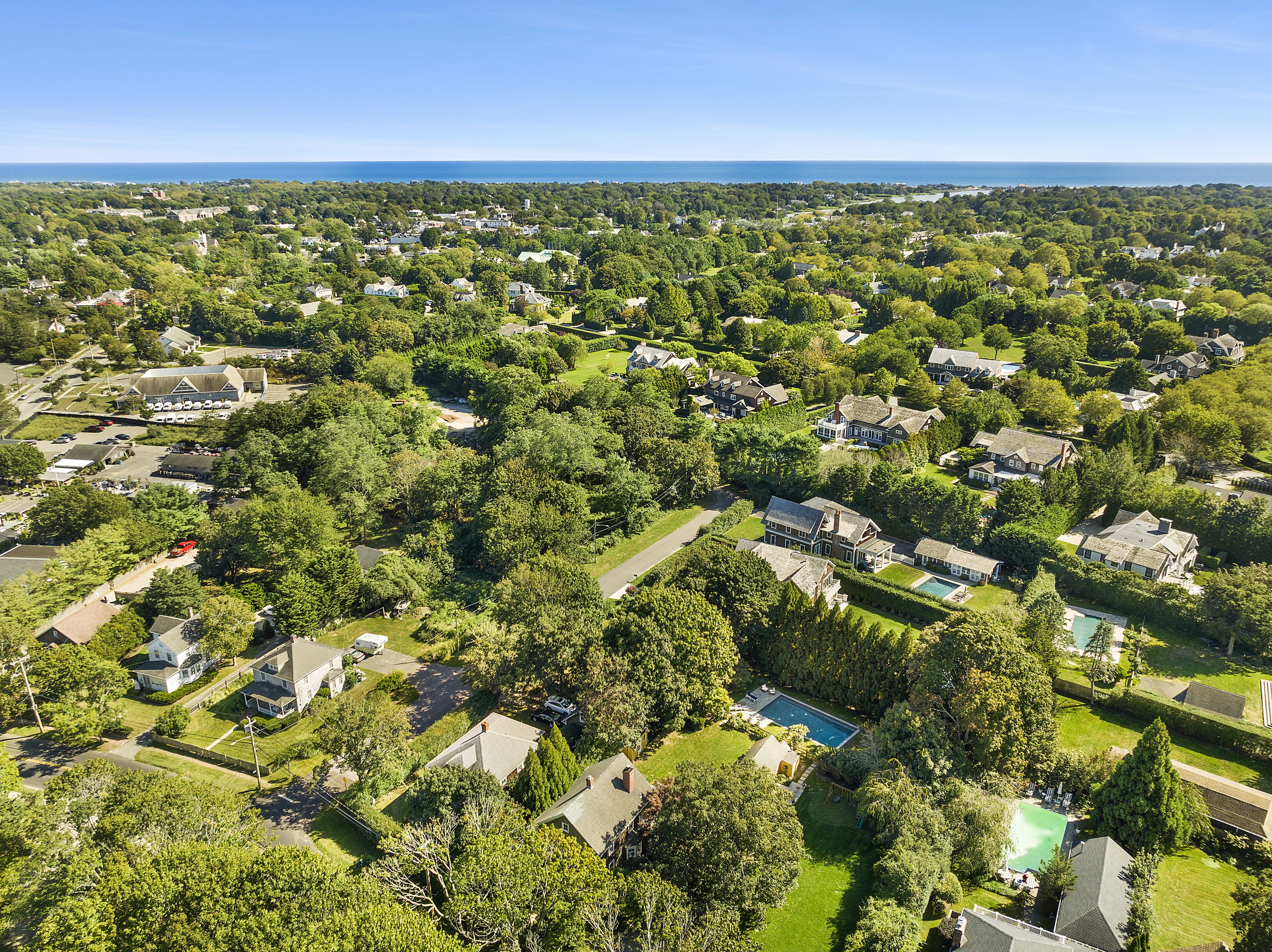 Vue aérienne d’un quartier résidentiel avec des maisons, des espaces verts et une grande étendue d’eau au loin.