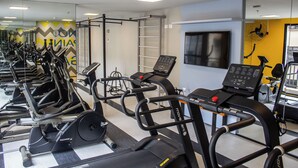 A gym with multiple treadmills, exercise bikes, and a wall-mounted TV. - Complete studio in the center of Curitiba. (Centro Curitiba)