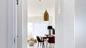 A bright, white-walled hallway leading to a dining area with a table and chairs. - Penthouse with the green kitchen and view of Brijuni in Peroj (Peroj)