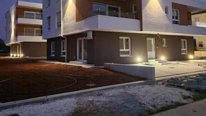 A modern multi-story residential building with balconies, a driveway, and a landscaped area. - Penthouse with the green kitchen and view of Brijuni in Peroj (Peroj)