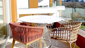 A modern outdoor balcony with a round table and wicker chairs, overlooking a residential area. - Penthouse with the green kitchen and view of Brijuni in Peroj (Peroj)
