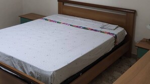 Camera singola con un letto e una testiera in legno, un piccolo comodino e una scrivania.
