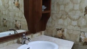 Un bagno con un lavandino bianco, un mobile contenitore in legno e uno specchio.