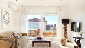 A modern living room with a sofa, coffee table, and a view of the cityscape through large windows. - Penthouse with the blue kitchen and view of Brijuni in Peroj (Peroj)