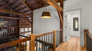 Un intérieur rustique avec des poutres apparentes, un escalier en bois et un luminaire suspendu.