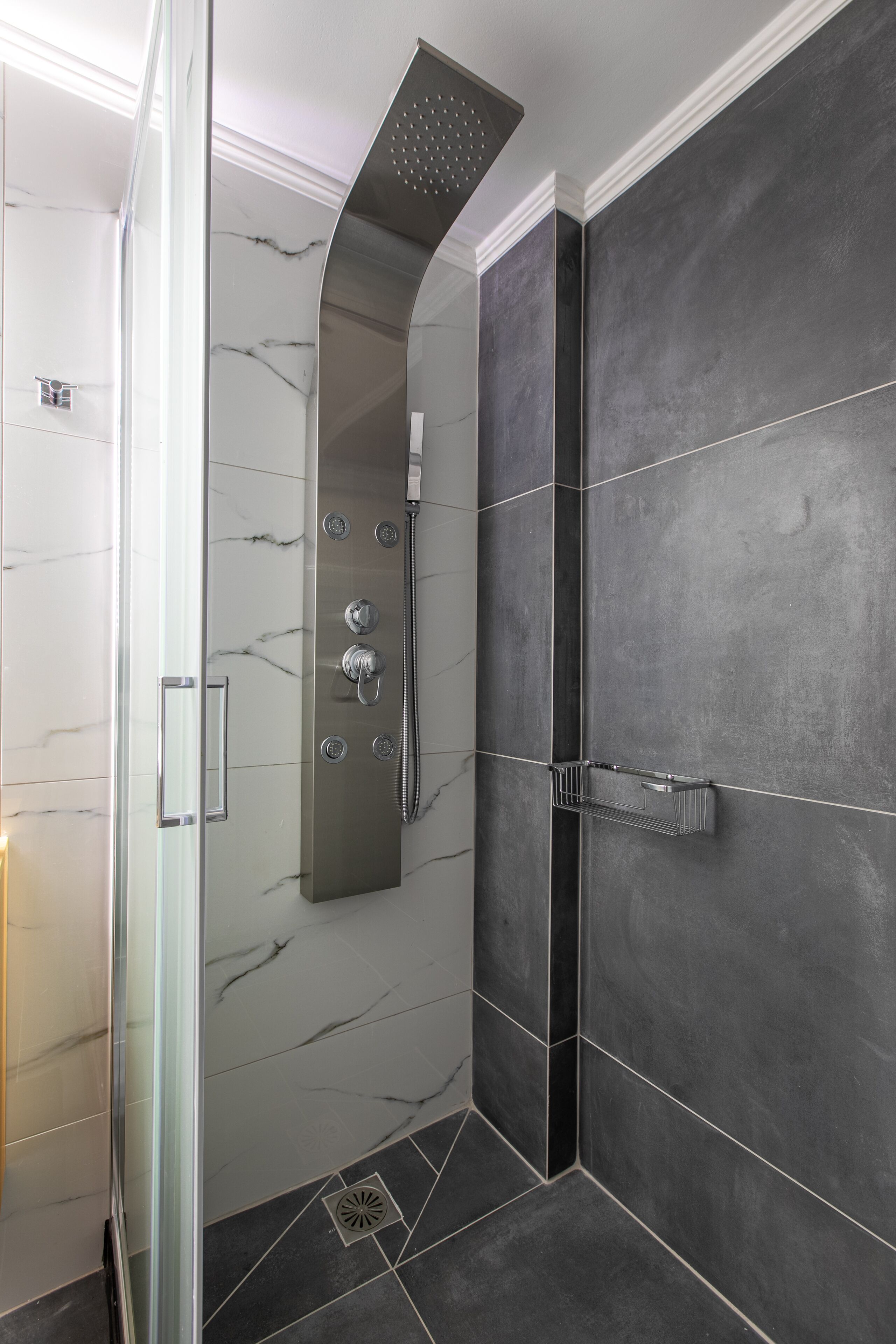 A modern shower with a glass door, a vertical rain showerhead, and a chrome faucet.