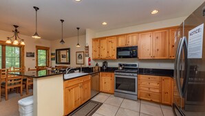 A modern kitchen with wooden cabinets, stainless steel appliances, and pendant lighting. - Family Ski Retreat w/ Hot Tub & Views (McHenry)