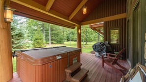 A wooden deck with a hot tub, a barbecue grill, and a wooden bench. - Family Ski Retreat w/ Hot Tub & Views (McHenry)