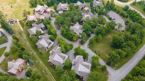 An aerial view of a residential area with multiple houses, roads, and green spaces. - Family Ski Retreat w/ Hot Tub & Views (McHenry)