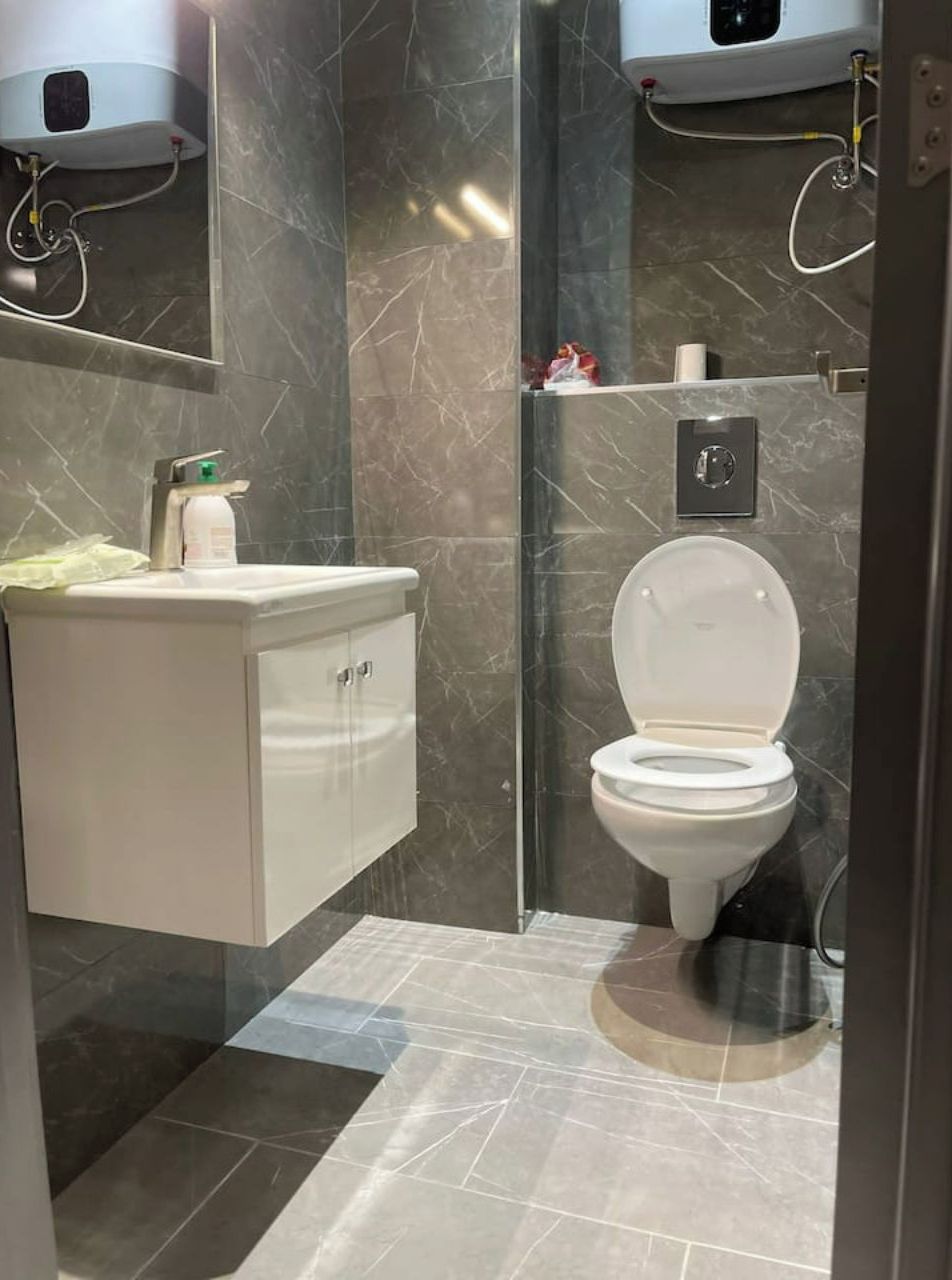 Et moderne badeværelse med toilet, vask og bruser.
