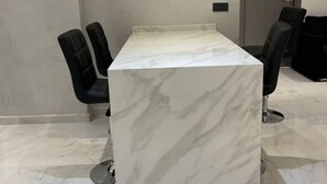 A modern conference room with a marble table, black chairs, and a door in the background. - Appartement de Luxe Avec vue sur mer à Malabata (Tanger)