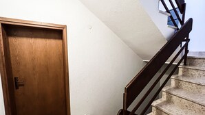 A wooden door, a staircase with a handrail, and a white wall with a window. - A cozy apartment, 1 km from the beach in a quiet neighborhood (Vrsar)