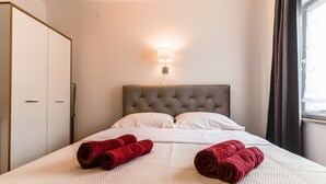 A hotel room with a bed, a wall-mounted light, a wardrobe, and a window with curtains. - A cozy apartment, 1 km from the beach in a quiet neighborhood (Vrsar)