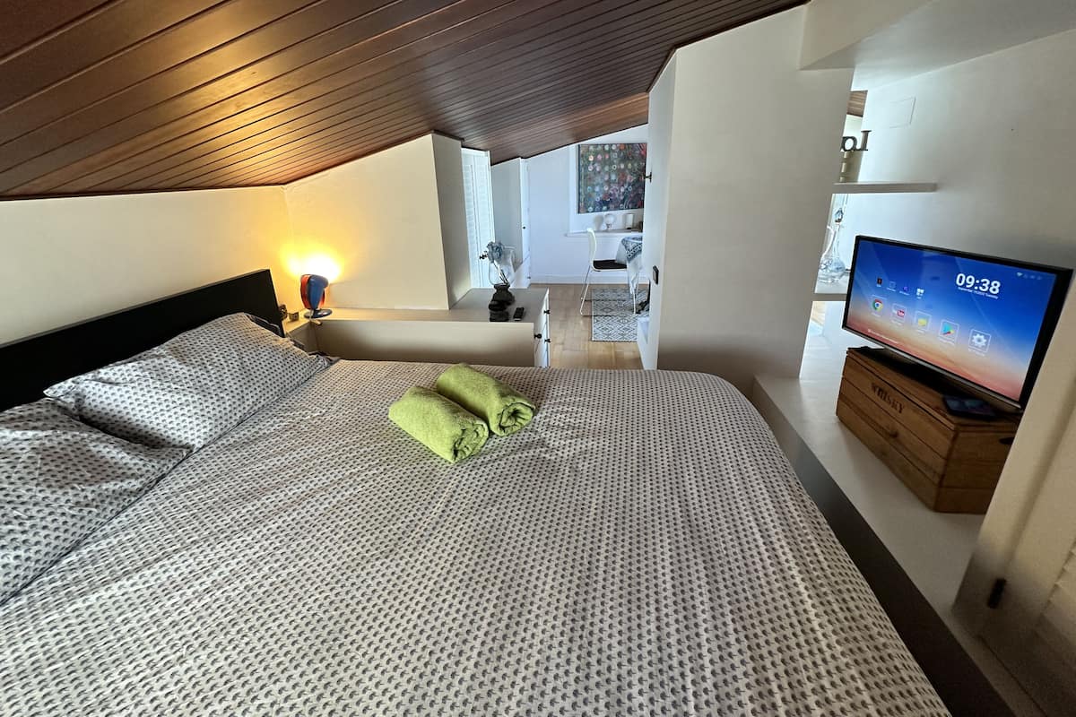 A hotel room with a bed, a TV, and a desk.