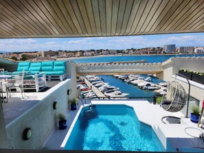 A rooftop pool with a view of a marina and cityscape. - Solo Atico Guest Suites (L'Escala)