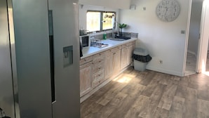 Una cocina moderna con armarios de madera, un refrigerador de acero inoxidable, un microondas y un lavamanos.