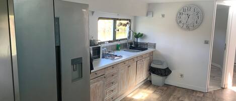 Uma cozinha moderna com armários de madeira, uma geladeira de aço inoxidável, micro-ondas e pia.