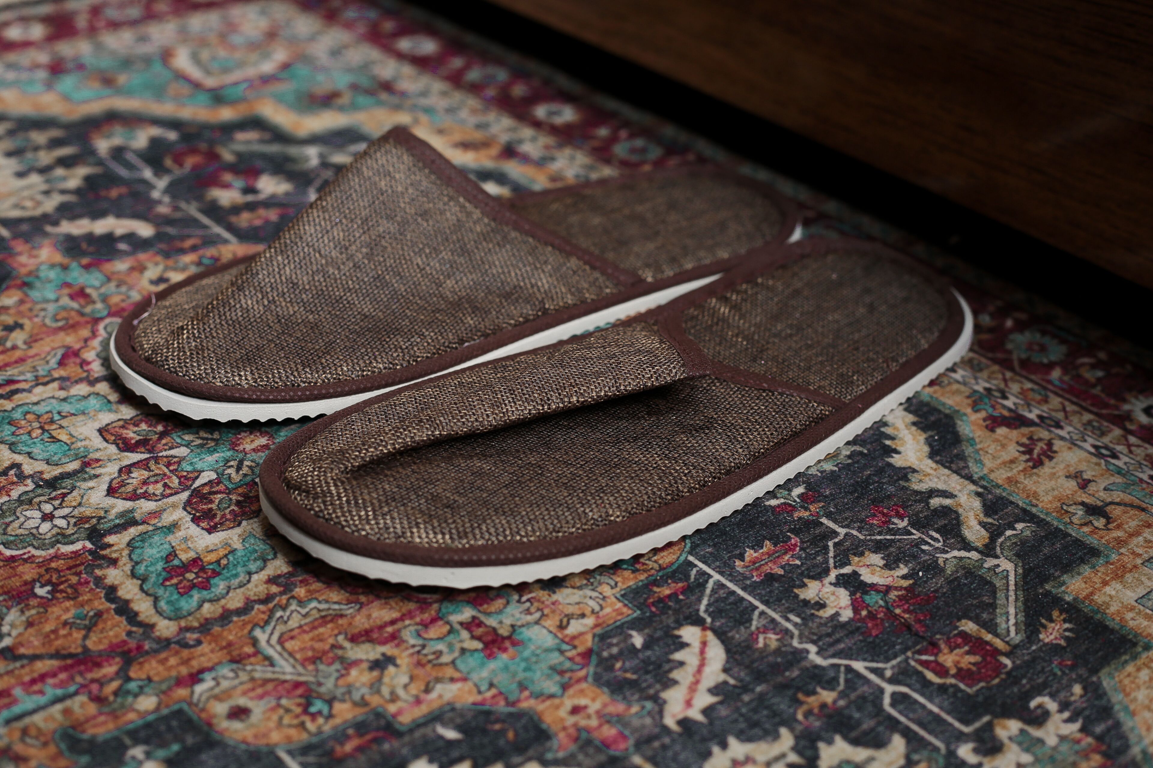 Bruine slippers van mesh op een kamerbreed tapijt met dessin.