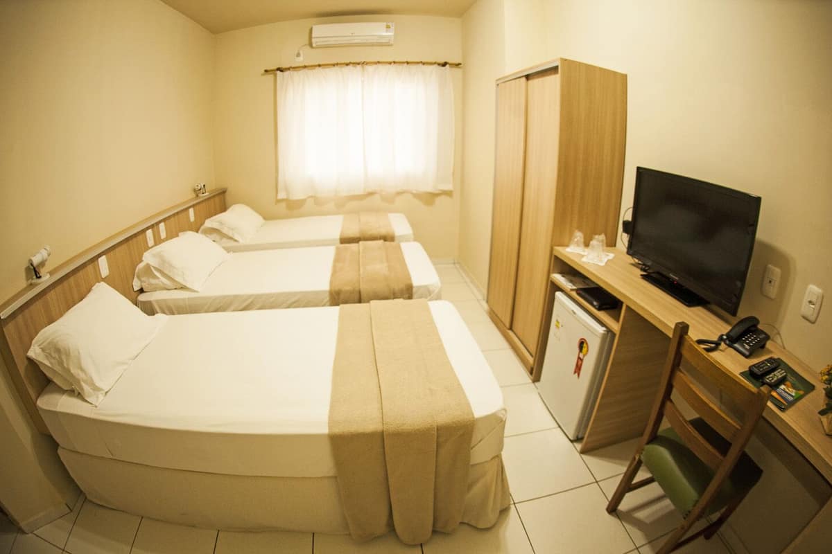 Habitación de hotel con dos camas individuales, un escritorio con televisor, un mini refrigerador y un armario.
