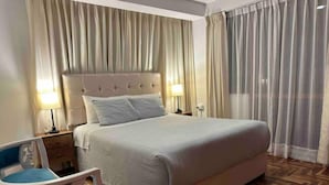 Ett hotellrum med en stor säng, två sänglampor, en stol och ett träparkettgolv.