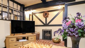 A living room with a chessboard, a television, and a large vase of flowers. - Bluebell Cottage (Rugeley)