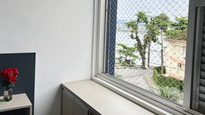 Ein Zimmer mit Fensterblick auf eine Straße mit Bäumen und Gebäuden.